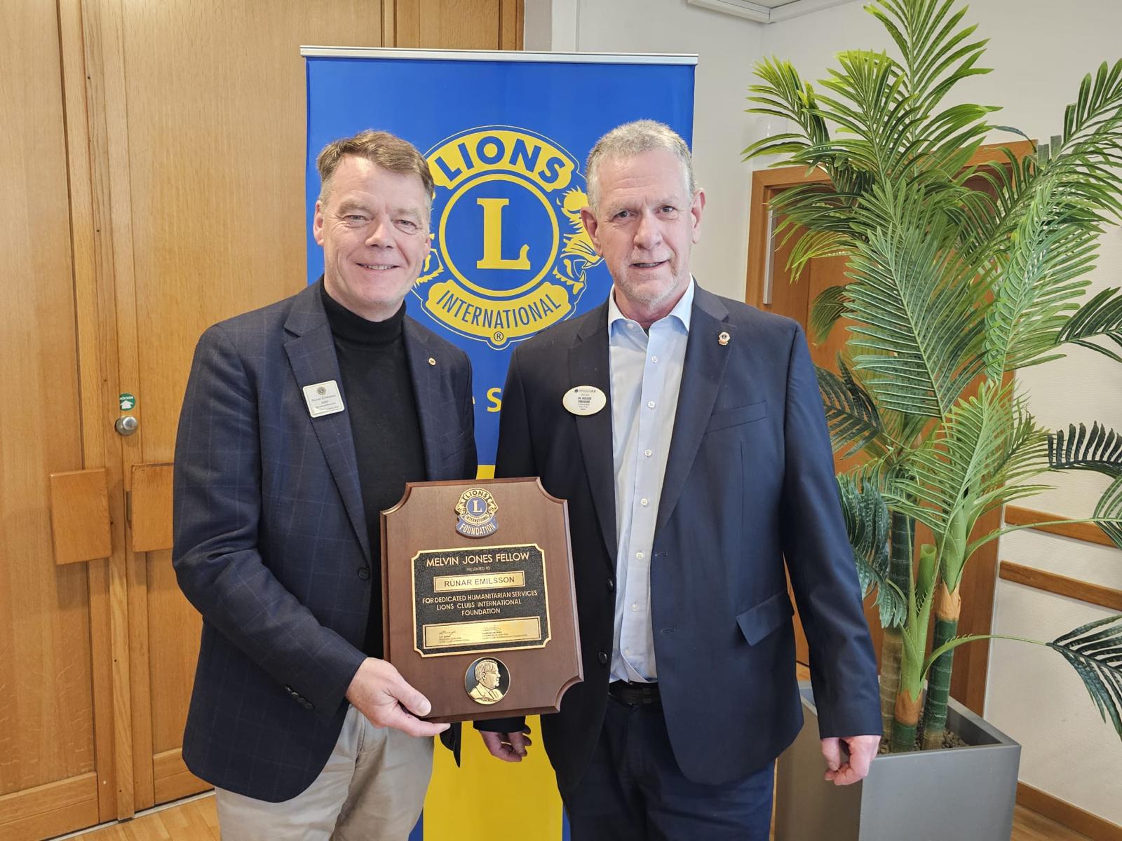 Rúnar Emilsson (links) vom Lions Club Viernheim erhält die Melvin Jones Fellowship von Distrikt-Governor Dr. Holger Drescher und hält die Auszeichnungsplakette vor einem Lions-Club-Banner.